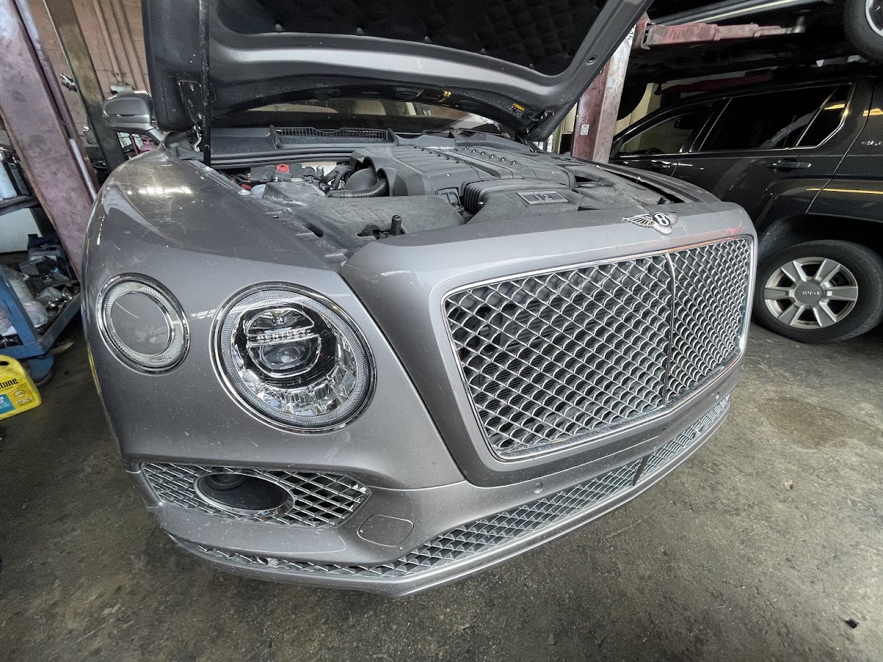 Expert mechanic using high-tech diagnostic tools on a luxury sedan in a clean, modern workshop
